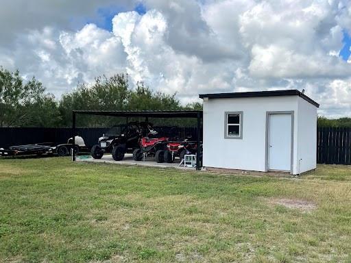 view of outdoor structure featuring a carport, fence, and an outdoor structure