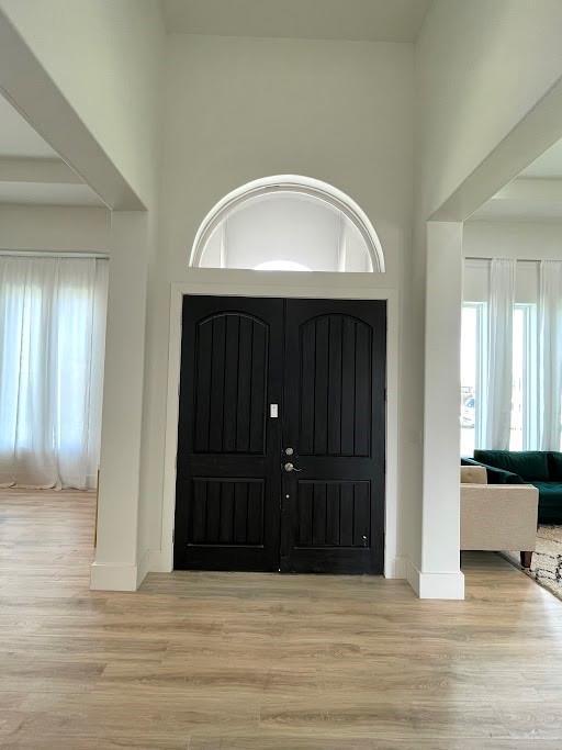 entryway with a high ceiling, baseboards, and wood finished floors