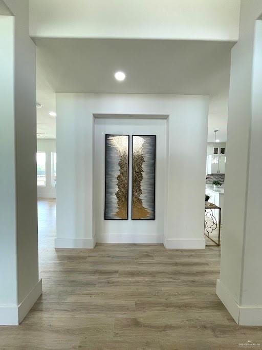 hall with light wood-style flooring and baseboards