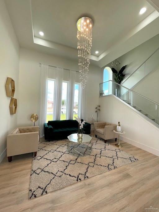 living area featuring wood finished floors, recessed lighting, a raised ceiling, and baseboards