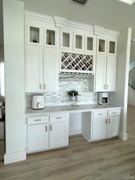 bar featuring tasteful backsplash, baseboards, visible vents, and light wood finished floors