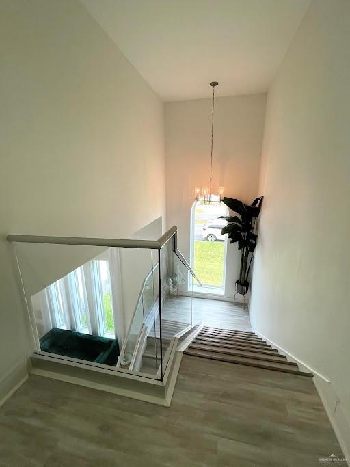 stairway with a chandelier, baseboards, a high ceiling, and wood finished floors