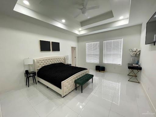 bedroom with recessed lighting, a raised ceiling, and baseboards