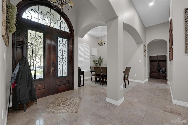 entryway featuring a high ceiling, baseboards, and a notable chandelier