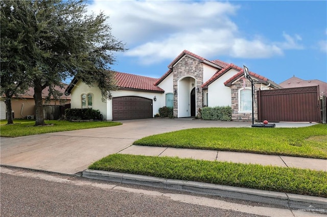 mediterranean / spanish house featuring stucco siding, a garage, stone siding, driveway, and a tiled roof