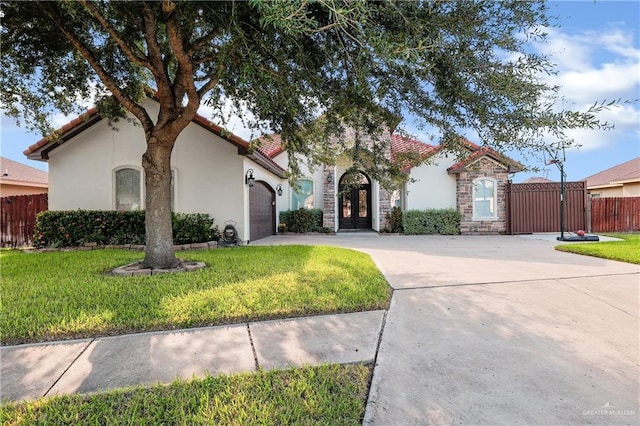 mediterranean / spanish-style home featuring driveway, a front yard, an attached garage, and stucco siding