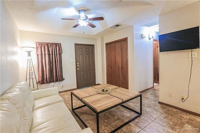 living room with ceiling fan and a textured ceiling