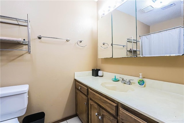 bathroom with tile patterned floors, vanity, a textured ceiling, and toilet