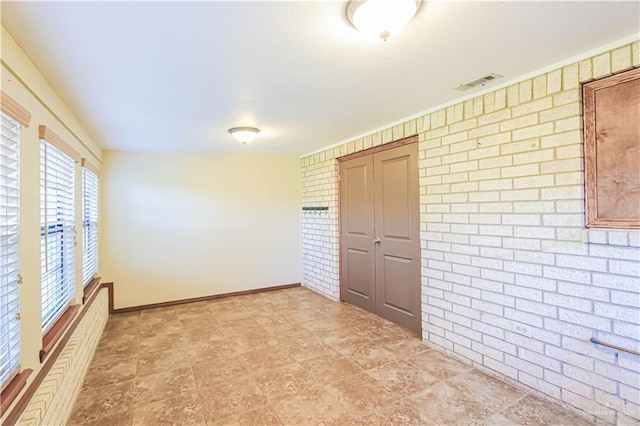 unfurnished room featuring brick wall