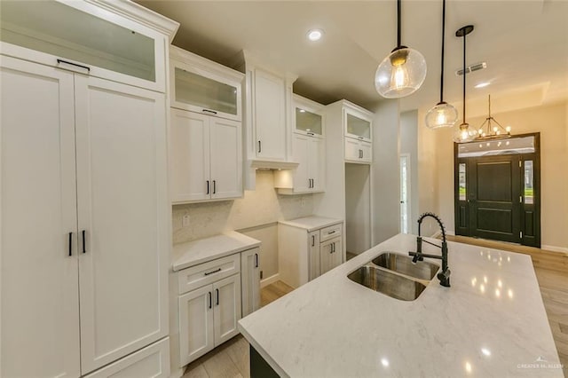 1310 S 9th St, Alamo, TX 78516 - kitchen featuring a sink, light wood finished floors, white cabinetry, backsplash, and pendant lighting
