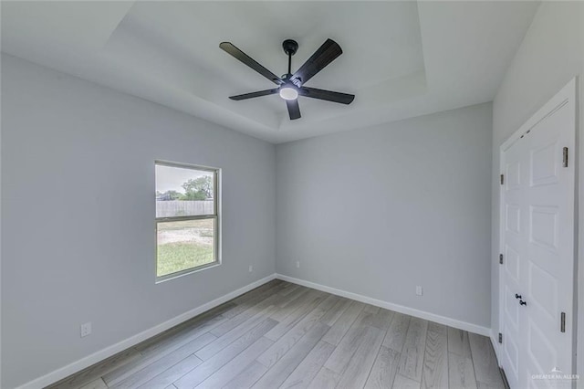1310 S 9th St, Alamo, TX 78516 - unfurnished bedroom featuring light wood-type flooring, a tray ceiling, baseboards, and a ceiling fan