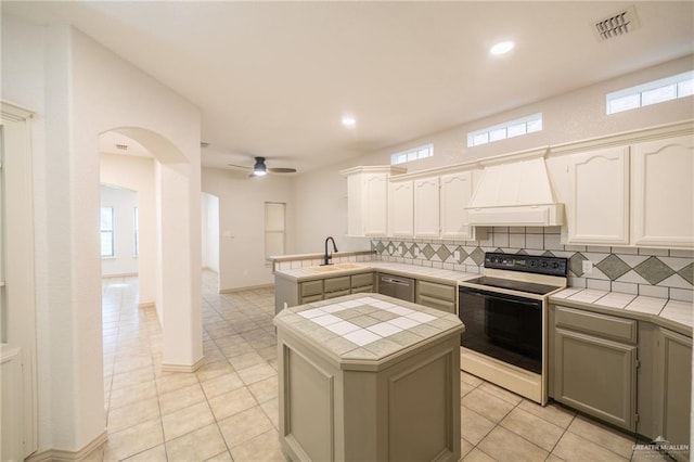 kitchen featuring premium range hood, white electric range oven, ceiling fan, a center island, and tile counters