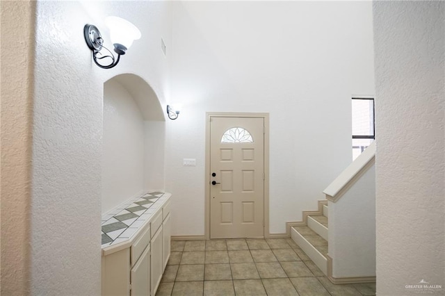 entryway featuring light tile patterned floors, plenty of natural light, and a high ceiling