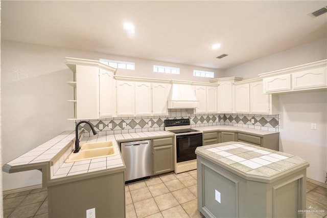 kitchen featuring kitchen peninsula, stainless steel dishwasher, custom exhaust hood, electric stove, and tile counters