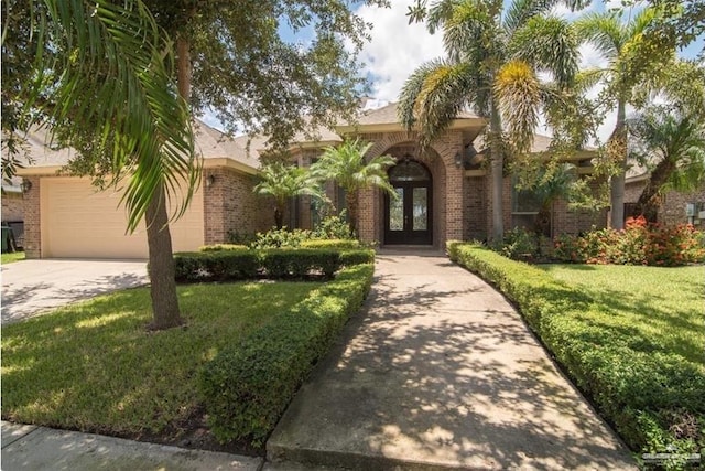 mediterranean / spanish-style house featuring a garage, a front yard, and french doors