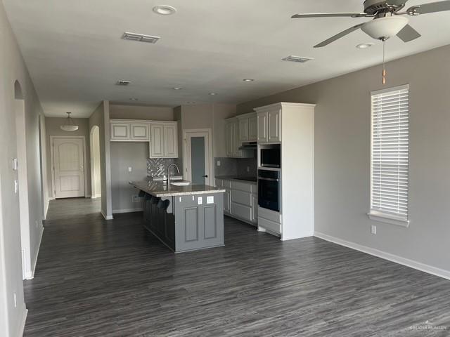 14405 Chalk Ridge Dr, Mcallen, TX 78504 - kitchen with oven, arched walkways, a ceiling fan, dark wood-style flooring, and recessed lighting