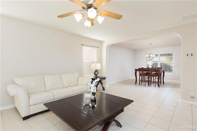 tiled living room with ceiling fan with notable chandelier