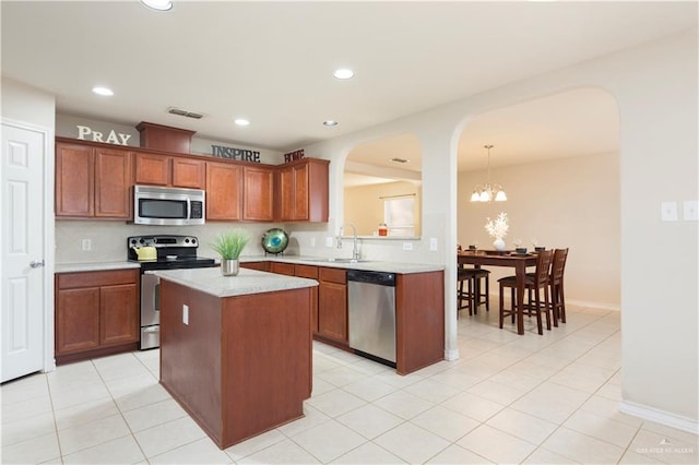 kitchen with appliances with stainless steel finishes, sink, decorative light fixtures, a chandelier, and a center island