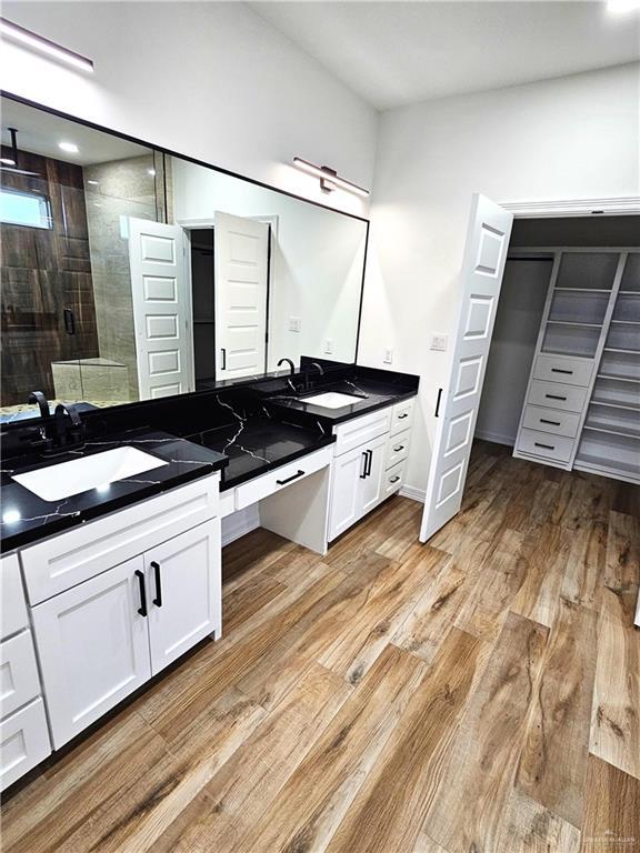 bathroom with wood-type flooring, vanity, and an enclosed shower