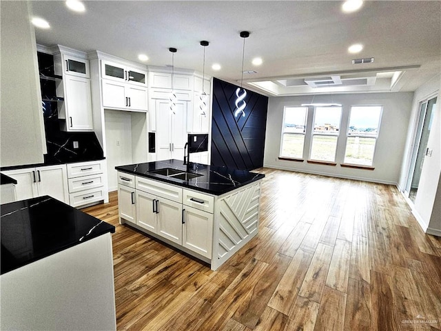 kitchen featuring white cabinets, a center island with sink, hanging light fixtures, and sink