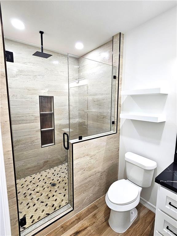 bathroom with vanity, wood-type flooring, a shower with shower door, and toilet