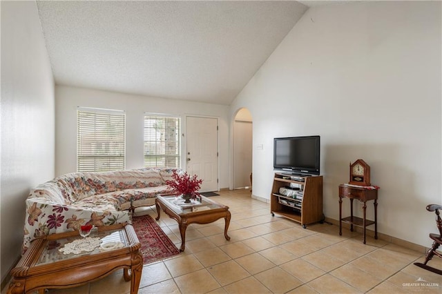 living area with high vaulted ceiling, arched walkways, baseboards, and light tile patterned floors