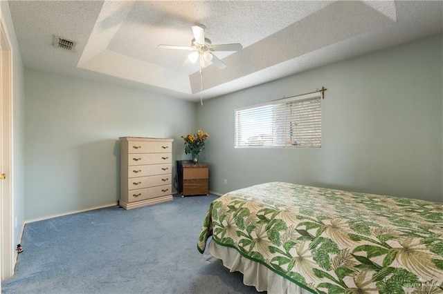 carpeted bedroom featuring a textured ceiling, a tray ceiling, visible vents, and baseboards