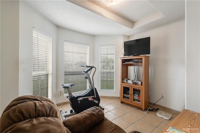 living area with a textured ceiling, light tile patterned flooring, and baseboards