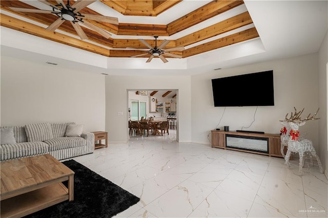 living room with a raised ceiling, a ceiling fan, baseboards, and a high ceiling