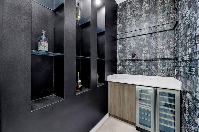 bar with wine cooler, light stone countertops, and light tile patterned flooring