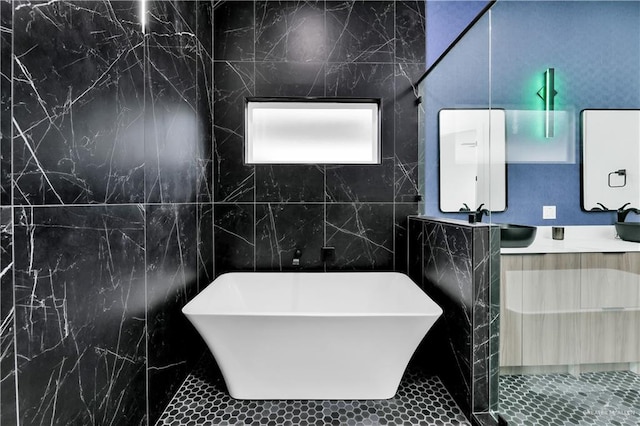 bathroom with vanity, a tub, and tile walls