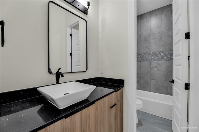 full bathroom featuring vanity, tiled shower / bath, and toilet