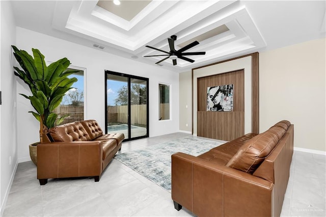 living room featuring a raised ceiling and ceiling fan