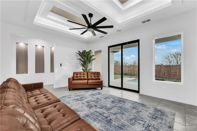 living room featuring light tile patterned floors, a tray ceiling, and ceiling fan