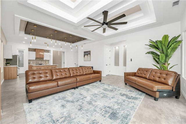 living room with a tray ceiling, ceiling fan, and light tile patterned flooring