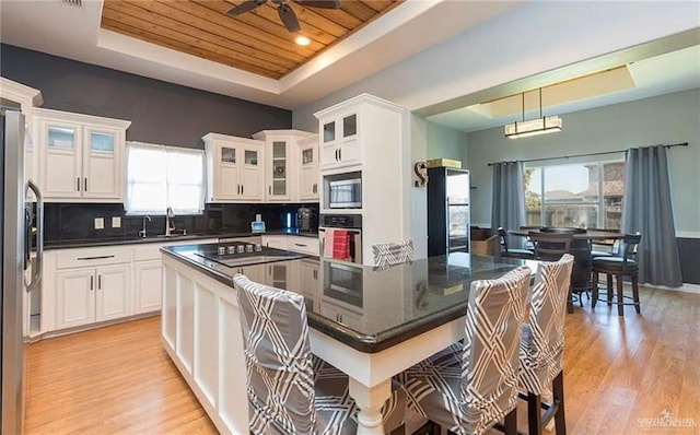 kitchen featuring a raised ceiling, white cabinets, wooden ceiling, appliances with stainless steel finishes, and light wood-type flooring