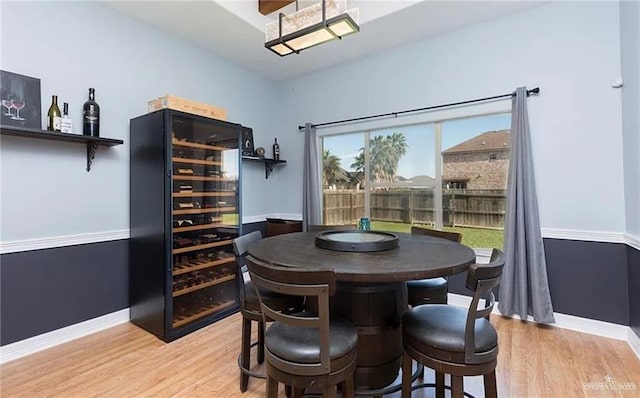 dining space with beverage cooler, wood finished floors, and baseboards