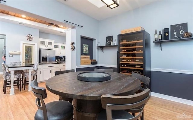 dining room featuring wine cooler, light wood-style flooring, and baseboards