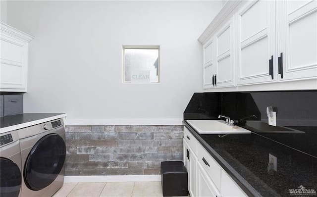 laundry area featuring light tile patterned floors, a sink, baseboards, independent washer and dryer, and cabinet space