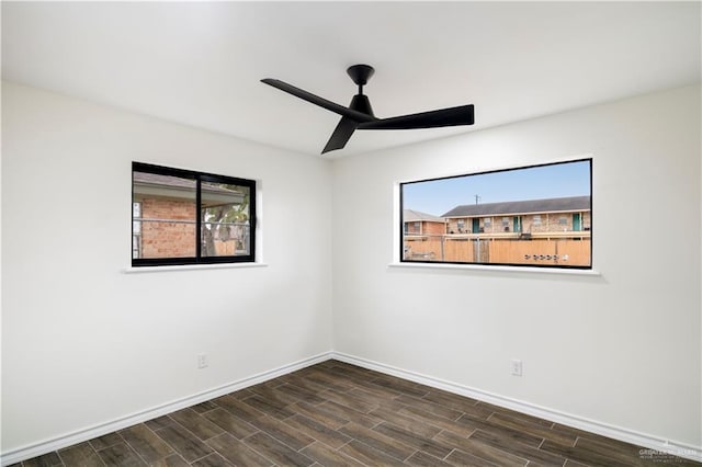 spare room with dark wood finished floors, a ceiling fan, and baseboards