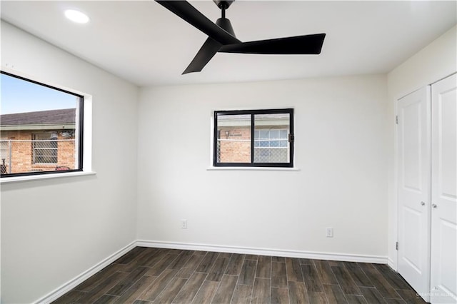 unfurnished bedroom with dark wood finished floors, multiple windows, and a closet