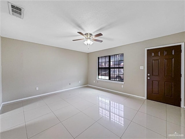 spare room featuring a textured ceiling, ceiling fan, and light tile patterned floors