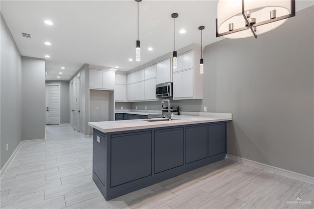 kitchen featuring pendant lighting, kitchen peninsula, sink, and white cabinets