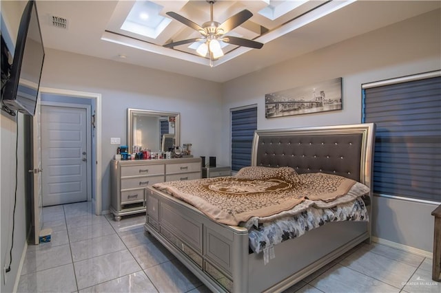 bedroom featuring a raised ceiling, a skylight, ceiling fan, and light tile patterned floors