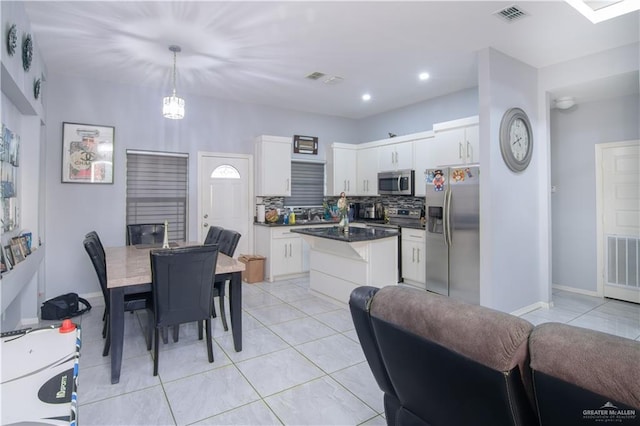 kitchen featuring white cabinets, appliances with stainless steel finishes, tasteful backsplash, and pendant lighting