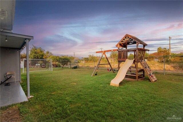 playground at dusk featuring a yard