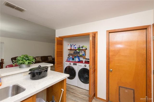 washroom with separate washer and dryer, sink, and light hardwood / wood-style flooring