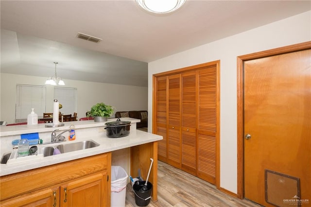 kitchen with sink, light wood-type flooring, hanging light fixtures, and a chandelier