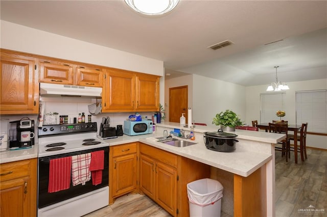 kitchen with kitchen peninsula, white appliances, sink, a chandelier, and light hardwood / wood-style floors