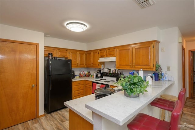 kitchen with black refrigerator, kitchen peninsula, light hardwood / wood-style floors, and electric stove